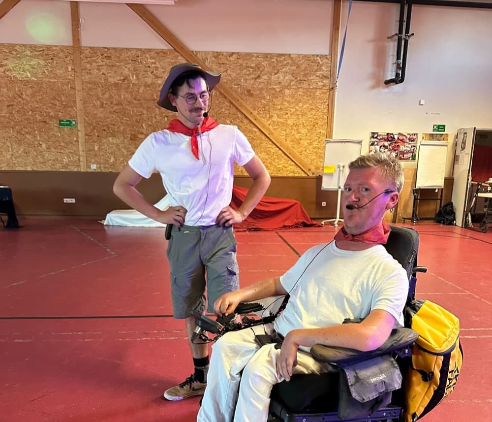 Un accompagnateur costumé partage un moment de complicité avec un jeune en fauteuil roulant